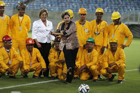 Brazil's President Dilma Rousseff (C) kicks the ball while standing near workers during the opening ceremony of the Arena das Dunas stadium, Brazil's President Dilma Rousseff (C) kicks the ball while standing near workers during the opening ceremony of the Arena das Dunas stadium,
