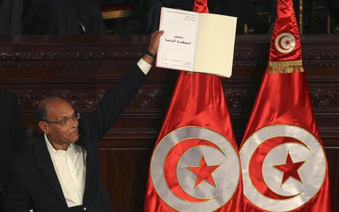 Tunisian President Moncef Marzouki holds a copy of the country's new constitution after signing it in Tunis January 27, 2014. Marzouki and t Tunisian President Moncef Marzouki holds a copy of the country's new constitution after signing it in Tunis January 27, 2014. Marzouki and t