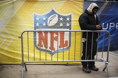 A worker looks at his phone in front of a banner on Broadway as preparations continue for Super Bowl XLVIII in New York January 28, 2014. RE A worker looks at his phone in front of a banner on Broadway as preparations continue for Super Bowl XLVIII in New York January 28, 2014. RE