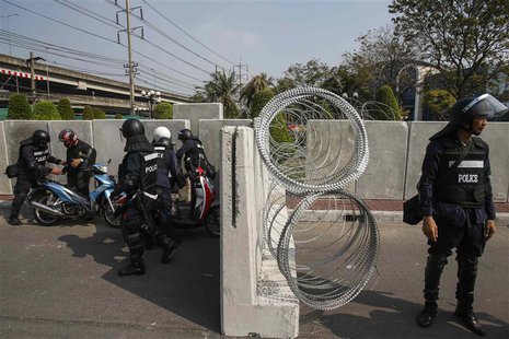 Riot police officers conduct a security check on motorcyclists near a barricade outside the compound of the Thai Royal Police club in Bangko Riot police officers conduct a security check on motorcyclists near a barricade outside the compound of the Thai Royal Police club in Bangko