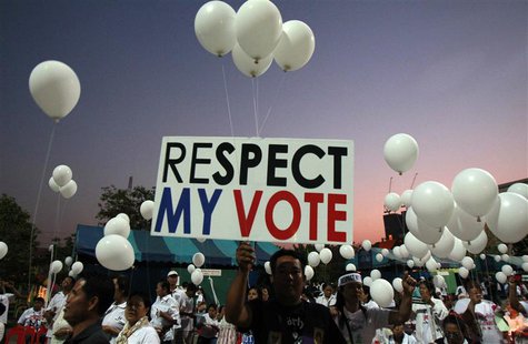 Pro-government supporters hold a placard and white balloons during an election campaign in Nonthaburi province, on the outskirts of Bangkok, Pro-government supporters hold a placard and white balloons during an election campaign in Nonthaburi province, on the outskirts of Bangkok,