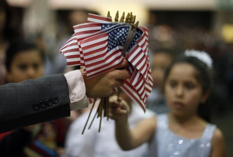 A man hands out U.S. flags at a naturalization ceremony for 3,703 new U.S. citizens from 130 countries, in Los Angeles, California, December A man hands out U.S. flags at a naturalization ceremony for 3,703 new U.S. citizens from 130 countries, in Los Angeles, California, December