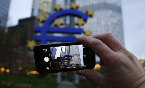 A man uses his mobile phone to take a picture of the euro sculpture outside the head quarters of the European Central Bank (ECB) in Frankfur A man uses his mobile phone to take a picture of the euro sculpture outside the head quarters of the European Central Bank (ECB) in Frankfur