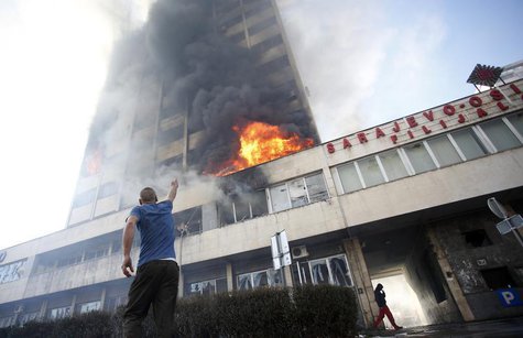 A man points as people attempt to put out a blaze at a government building in Tuzla February 7, 2014. REUTERS/Dado Ruvic A man points as people attempt to put out a blaze at a government building in Tuzla February 7, 2014. REUTERS/Dado Ruvic