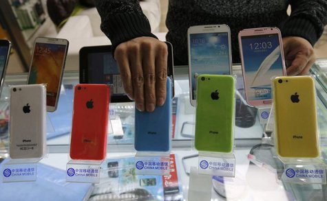 A clerk arranges Apple's iPhone 5C phones on racks bearing the logo of China Mobile, at a mobile phone shop in Beijing December 23, 2013. RE A clerk arranges Apple's iPhone 5C phones on racks bearing the logo of China Mobile, at a mobile phone shop in Beijing December 23, 2013. RE