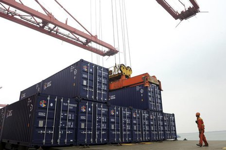 A worker stands near a crane unloading shipping containers from a cargo ship at a port in Lianyungang, Jiangsu province November 8, 2013. RE A worker stands near a crane unloading shipping containers from a cargo ship at a port in Lianyungang, Jiangsu province November 8, 2013. RE