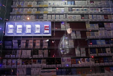 A woman is reflected in a window displaying packs of cigarettes on a street in Russia's Siberian city of Krasnoyarsk January 24, 2013. REUTE A woman is reflected in a window displaying packs of cigarettes on a street in Russia's Siberian city of Krasnoyarsk January 24, 2013. REUTE