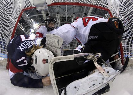 Team USA's Jocelyne Lamoureux (17) crashes into Switzerland's goalie Florence Schelling (R) as Switzerland's Laura Benz defends during the t Team USA's Jocelyne Lamoureux (17) crashes into Switzerland's goalie Florence Schelling (R) as Switzerland's Laura Benz defends during the t