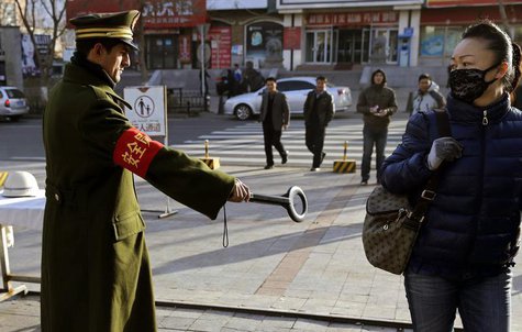 A pedestrian reacts as a security officer holds out a detector on a street in Urumqi, Xinjiang Uighur autonomous region, November 17, 2013. A pedestrian reacts as a security officer holds out a detector on a street in Urumqi, Xinjiang Uighur autonomous region, November 17, 2013.