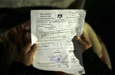 Suhad al-Katib, a Palestinian woman patient who suffers cancer holds paperwork inside her house after she was not allowed to enter Israel, i Suhad al-Katib, a Palestinian woman patient who suffers cancer holds paperwork inside her house after she was not allowed to enter Israel, i