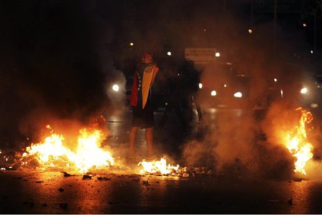 A demonstrator stands with a flag on his back as demonstrators block the city's main highway during a protest against President Nicolas Madu A demonstrator stands with a flag on his back as demonstrators block the city's main highway during a protest against President Nicolas Madu