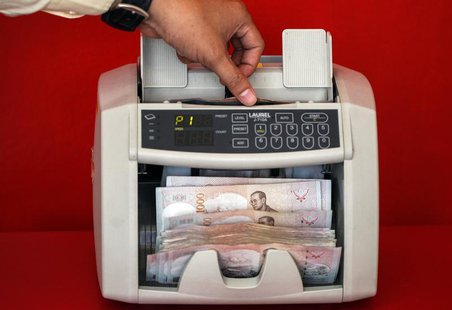 A pawn shop worker uses a machine to count Thai Baht banknotes as he prepares to purchase items from customers at Easy Money Pawn shop in Ba A pawn shop worker uses a machine to count Thai Baht banknotes as he prepares to purchase items from customers at Easy Money Pawn shop in Ba