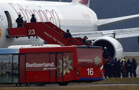 A passenger (4th L) climbs down an airplane ladder with his hands on his head as police officers stand around hijacked Ethiopian Airlines fl A passenger (4th L) climbs down an airplane ladder with his hands on his head as police officers stand around hijacked Ethiopian Airlines fl
