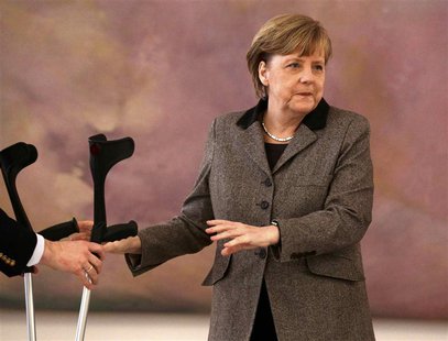 An aide take the crutches of German Chancellor Angela Merkel as she attends the appointment ceremony of the new Agriculture Minister Christi An aide take the crutches of German Chancellor Angela Merkel as she attends the appointment ceremony of the new Agriculture Minister Christi