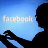 A man is silhouetted against a video screen with an Facebook logo as he poses with an Dell laptop in this photo illustration taken in the ce A man is silhouetted against a video screen with an Facebook logo as he poses with an Dell laptop in this photo illustration taken in the ce