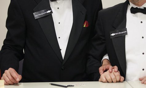 Two men, both wearing signs that read "he's the groom", hold hands shortly after midnight after getting a civil union when Colorado's civil Two men, both wearing signs that read "he's the groom", hold hands shortly after midnight after getting a civil union when Colorado's civil