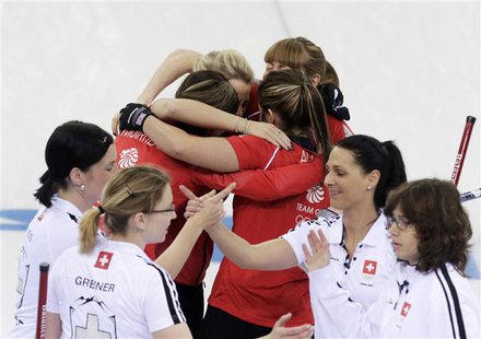 Britain's curling team celebrates with a group hug after winning in their women's bronze medal curling game against Switzerland (foreground) Britain's curling team celebrates with a group hug after winning in their women's bronze medal curling game against Switzerland (foreground)