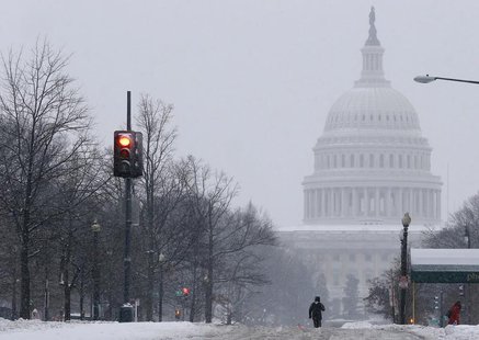 A pedestrian walks up the middle of North Capitol Street towards the U.S. Capitol building, on largely deserted streets, as a major snow sto A pedestrian walks up the middle of North Capitol Street towards the U.S. Capitol building, on largely deserted streets, as a major snow sto
