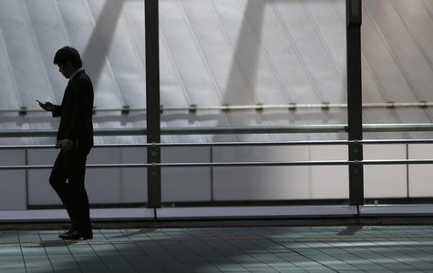 A man holding his mobile phone walks on an overpass at Tokyo's business district February 20, 2014. REUTERS/Yuya Shino A man holding his mobile phone walks on an overpass at Tokyo's business district February 20, 2014. REUTERS/Yuya Shino