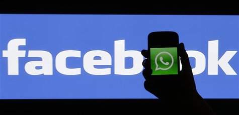 A woman holds a smartphone displaying WhatApps' logo in front of the screen with the Facebook logo in this photo illustration taken in Pragu A woman holds a smartphone displaying WhatApps' logo in front of the screen with the Facebook logo in this photo illustration taken in Pragu