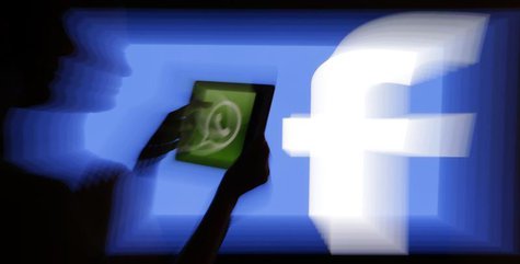 A woman holds a tablet displaying WhatsApp's logo in front of the screen with the Facebook logo in this photo illustration taken in Prague F A woman holds a tablet displaying WhatsApp's logo in front of the screen with the Facebook logo in this photo illustration taken in Prague F