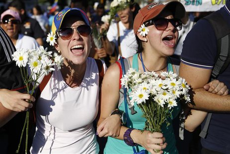 Supporters of opposition leader Leopoldo Lopez hold flowers and shout during a rally to promote peace in Caracas February 20, 2014. REUTERS/ Supporters of opposition leader Leopoldo Lopez hold flowers and shout during a rally to promote peace in Caracas February 20, 2014. REUTERS/