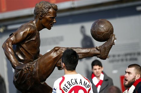 Arsenal fans look at a statue of former striker Dennis Bergkamp after it was unveiled before their English Premier League soccer match again Arsenal fans look at a statue of former striker Dennis Bergkamp after it was unveiled before their English Premier League soccer match again