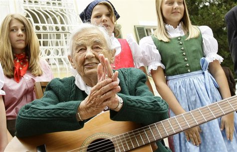 Maria von Trapp, daughter of Austrian Baron Georg von Trapp, prepares to play a guitar and sing with traditionally dressed children in front Maria von Trapp, daughter of Austrian Baron Georg von Trapp, prepares to play a guitar and sing with traditionally dressed children in front