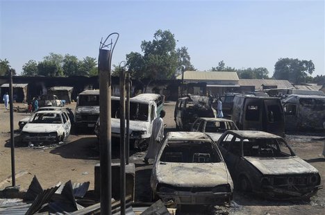 A man walks between vehicles that were destroyed during an attack by Boko Haram militants in Bama, Borno State, February 20, 2014. REUTERS/S A man walks between vehicles that were destroyed during an attack by Boko Haram militants in Bama, Borno State, February 20, 2014. REUTERS/S