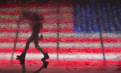 A woman is reflected in the wet pavement as she walks past a U.S. flag billboard in Times Square during a rare winter thunderstorm in New Yo A woman is reflected in the wet pavement as she walks past a U.S. flag billboard in Times Square during a rare winter thunderstorm in New Yo