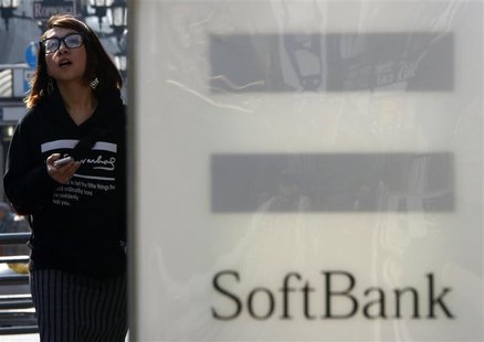 A woman holding her smartphone walks past an advertisement board of SoftBank Corp outside its branch in Tokyo February 25, 2014. REUTERS/Yuy A woman holding her smartphone walks past an advertisement board of SoftBank Corp outside its branch in Tokyo February 25, 2014. REUTERS/Yuy