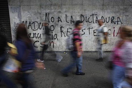 Pedestrians walk past a wall covered with graffiti that reads, "No to the dictatorship of Maduro" at the district of Chacao in Caracas Febru Pedestrians walk past a wall covered with graffiti that reads, "No to the dictatorship of Maduro" at the district of Chacao in Caracas Febru