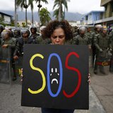 A demonstrator holds a placard as she stands in front of national guards during a protest near the Cuba's Embassy in Caracas February 25, 20 A demonstrator holds a placard as she stands in front of national guards during a protest near the Cuba's Embassy in Caracas February 25, 20