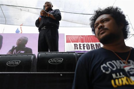A security agent stands under a stage as protest leader Suthep Thaugsuban addresses anti-government protesters in their encampment in centra A security agent stands under a stage as protest leader Suthep Thaugsuban addresses anti-government protesters in their encampment in centra