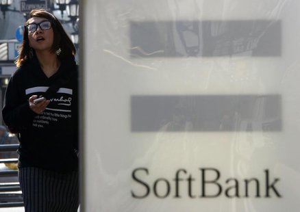 A woman holding her smartphone walks past an advertisement board of SoftBank Corp outside its branch in Tokyo February 25, 2014. REUTERS/Yuy A woman holding her smartphone walks past an advertisement board of SoftBank Corp outside its branch in Tokyo February 25, 2014. REUTERS/Yuy