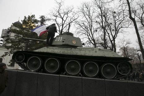 An ethnic Russian Ukrainian man holds the Crimea flag on top of an old Soviet tank during rallies near the Crimean parliament building in Si An ethnic Russian Ukrainian man holds the Crimea flag on top of an old Soviet tank during rallies near the Crimean parliament building in Si