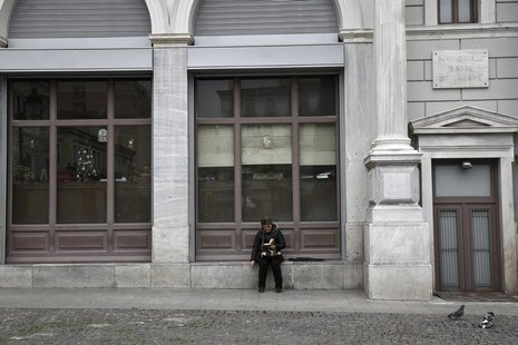 A woman reads a book outside a National Bank branch in Athens December 31, 2013. REUTERS/Yorgos Karahalis A woman reads a book outside a National Bank branch in Athens December 31, 2013. REUTERS/Yorgos Karahalis