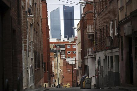 A man searches for food in a garbage container along a street, with the Four Towers business district pictured in the background, in Tetuan, A man searches for food in a garbage container along a street, with the Four Towers business district pictured in the background, in Tetuan,