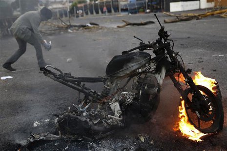 An anti-government demonstrator walks behind a burning motorcycle during a protest in San Cristobal, about 410 miles (660 km) southwest of C An anti-government demonstrator walks behind a burning motorcycle during a protest in San Cristobal, about 410 miles (660 km) southwest of C