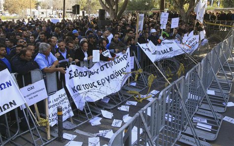 Demonstrators hold signs and banners outside Cyprus’s parliament as they protest plans by the government to sell off state-owned enterprises Demonstrators hold signs and banners outside Cyprus’s parliament as they protest plans by the government to sell off state-owned enterprises