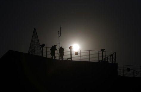 A visitor (L) looks towards the north through a pair of binoculars near the demilitarized zone separating the two Koreas, in Paju, 55 km (34 A visitor (L) looks towards the north through a pair of binoculars near the demilitarized zone separating the two Koreas, in Paju, 55 km (34