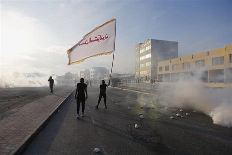An anti-government protester waves a flag with a religious slogan on it as he confronts riot police amidst teargas, during clashes after the An anti-government protester waves a flag with a religious slogan on it as he confronts riot police amidst teargas, during clashes after the