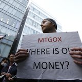 Kolin Burges, a self-styled cryptocurrency trader and former software engineer from London, holds a placard to protest against Mt. Gox, in f Kolin Burges, a self-styled cryptocurrency trader and former software engineer from London, holds a placard to protest against Mt. Gox, in f