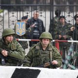 Military personnel, believed to be Russian servicemen, stand outside a Ukranian military post as Ukranian servicemen look on from behind a g Military personnel, believed to be Russian servicemen, stand outside a Ukranian military post as Ukranian servicemen look on from behind a g