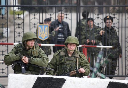 Military personnel, believed to be Russian servicemen, stand outside a Ukranian military post as Ukranian servicemen look on from behind a g Military personnel, believed to be Russian servicemen, stand outside a Ukranian military post as Ukranian servicemen look on from behind a g