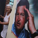 A woman smiles as she stands next to a poster of Venezuela's late President Hugo Chavez at the 23 de Enero neighbourhood in Caracas March 5, A woman smiles as she stands next to a poster of Venezuela's late President Hugo Chavez at the 23 de Enero neighbourhood in Caracas March 5,
