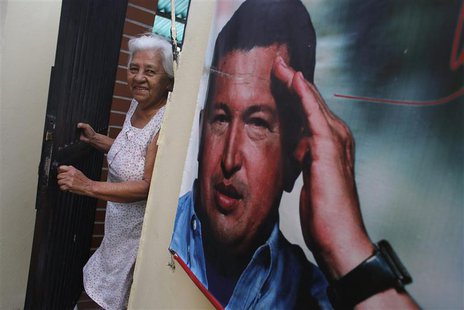 A woman smiles as she stands next to a poster of Venezuela's late President Hugo Chavez at the 23 de Enero neighbourhood in Caracas March 5, A woman smiles as she stands next to a poster of Venezuela's late President Hugo Chavez at the 23 de Enero neighbourhood in Caracas March 5,
