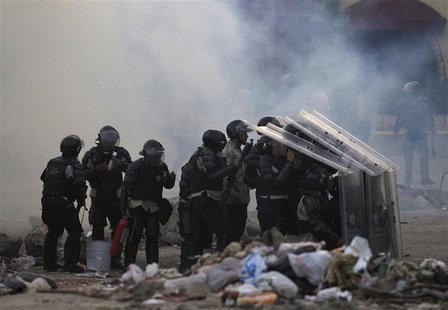 Riot police take cover from stones throw by anti-government protesters during a protest against the government of Venezuela's President Nico Riot police take cover from stones throw by anti-government protesters during a protest against the government of Venezuela's President Nico