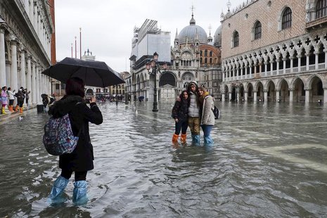 Tourists pose for a photo in a flooded St. Mark's Square during a period of seasonal high water in Venice January 31, 2014. REUTERS/Manuel S Tourists pose for a photo in a flooded St. Mark's Square during a period of seasonal high water in Venice January 31, 2014. REUTERS/Manuel S