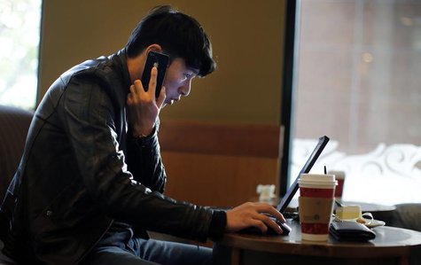 A man talks on the phone as he surfs the internet on his laptop at a local coffee shop in downtown Shanghai November 28, 2013. REUTERS/Carlo A man talks on the phone as he surfs the internet on his laptop at a local coffee shop in downtown Shanghai November 28, 2013. REUTERS/Carlo